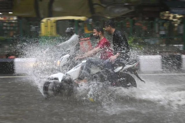 A motorcyclist drives through a water logged street during a heavy downpour in New Delhi, India, Sunday, July 9, 2023. (Photo by Manish Swarup/AP Photo)