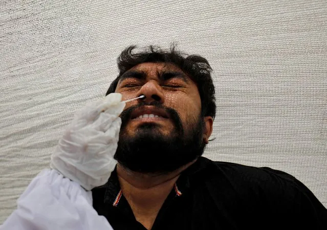 A man reacts as a healthcare worker collects a swab sample from him for a rapid antigen test during a testing campaign for coronavirus disease (COVID-19), at a kiosk in Ahmedabad, India, March 22, 2021. (Photo by Amit Dave/Reuters)