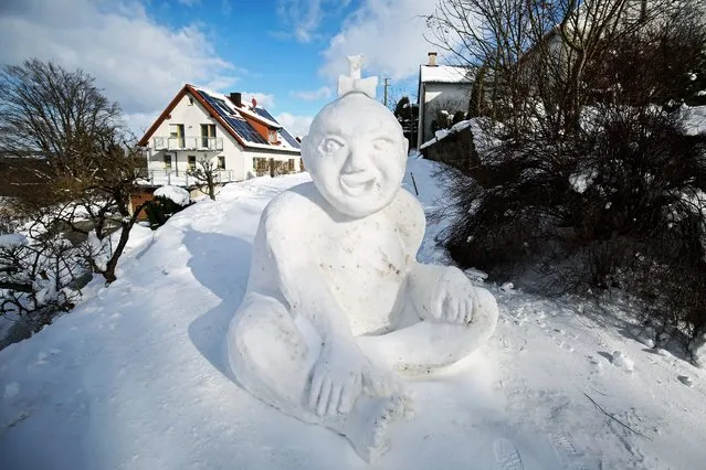 A snow sculpture in the shape of a smiling baby sits in on a path in Wohnsgehaig, Germany, 08 February 2015. (Photo by David Ebener/EPA)