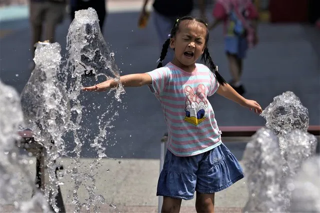 A child reacts to a water fountain in Beijing, Monday, August 14, 2023. (Photo by Ng Han Guan/AP Photo)