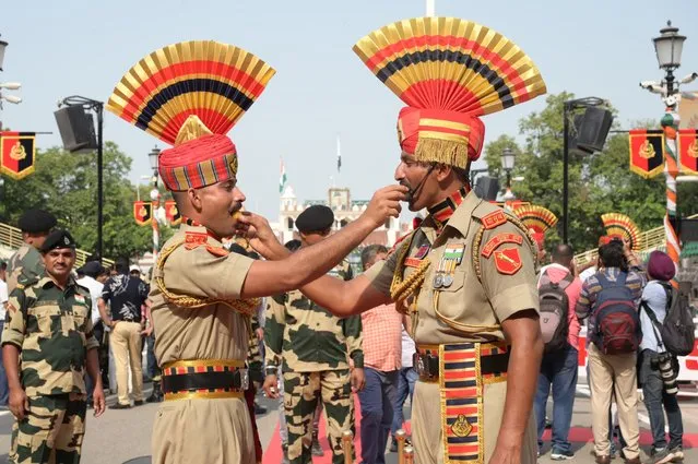 Indian Border Security Force (BSF) personnel offers sweets to each other on the occasion of the country's 77th Independence Day celebrations at India-Pakistan Wagah Border post, some 35 km from Amritsar on August 15, 2023. (Photo by Narinder Nanu/AFP Photo)