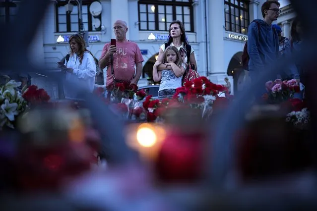 People stand next to an informal street memorial with lit candles for Wagner Group's military group members killed in a plane crash on Wednesday, near the Kremlin in Moscow, Russia, Sunday, August 27, 2023. Prigozhin was aboard a plane that crashed north of Moscow killing all 10 people on board. Russia's Investigative Committee said forensic and genetic testing identified all 10 bodies recovered from the crash, and the identities “conform with the manifest”. (Photo by Alexander Zemlianichenko/AP Photo)