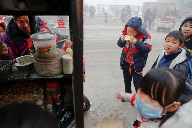 Children buy food outside their school as heavy smog blankets Shenfang in Hebei province, on an very polluted day December 20, 2016. (Photo by Damir Sagolj/Reuters)