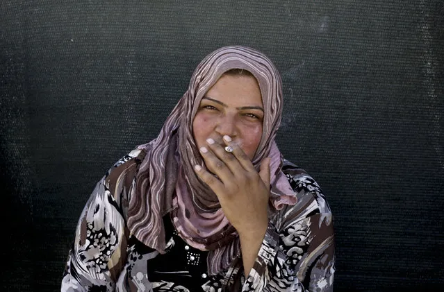 In this Wednesday, September 11, 2013 file photo, a Syrian refugee woman smokes a cigarette outside of her tent at a temporary refugee camp, in the eastern Lebanese town of al-Faour in the Bekaa valley, near the border with Syria. (Photo by Nariman El-Mofty/AP Photo)