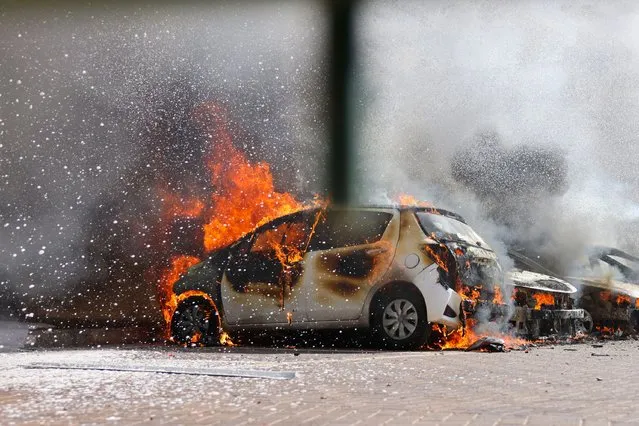 Cars are seen on fire following a rocket attack from the Gaza Strip in Ashkelon, southern Israel, on October 7, 2023. Barrages of rockets were fired at Israel from the blockaded Gaza Strip at dawn as militants from the Palestinian enclave infiltrated Israel, with at least one person killed, the army and medics said. (Photo by Ahmad Gharabli/AFP Photo)