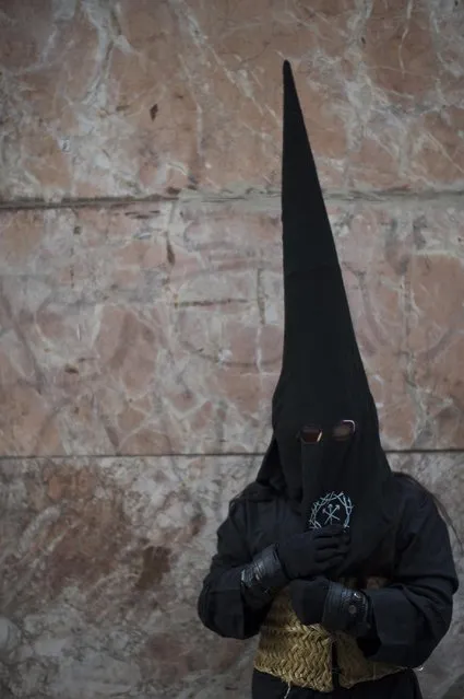 A masked penitent prepares to take part in the procession of the “Silencio del Santisimo Cristo del Rebate” brotherhood, during Holy Week in Tarazona, northern Spain, Tuesday, March 31, 2015. Hundreds of processions take place throughout Spain during the Easter Holy Week. (Photo by Alvaro Barrientos/AP Photo)
