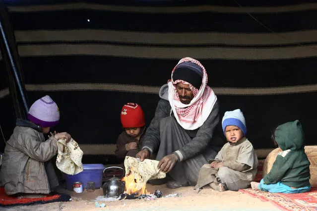 Stateless Arabs from an ethnic group known as Bedoon, who are believed to be descendants of nomadic Bedouins, sit around a fire in a makeshift shelter in a desert west of Al-Jawf region, Saudi Arabia, December 31, 2016. (Photo by Mohamed Al Hwaity/Reuters)