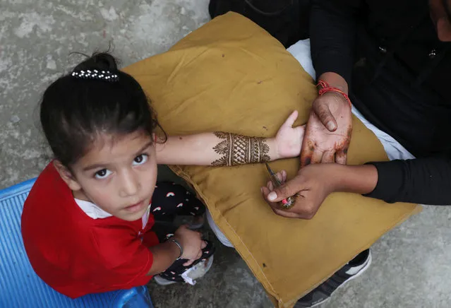 A Kashmiri Muslim girl gets her arm designed with Henna ahead of Eid-al-Adha in Srinagar, the summer capital of Indian Kashmir, 19 July 2021. Eid al-Adha is the holiest of the two Muslim holidays celebrated each year, it marks the yearly Muslim pilgrimage (Hajj) to visit Mecca, the holiest place in Islam. Muslims slaughter a sacrificial animal and split the meat into three parts, one for the family, one for friends and relatives, and one for the poor and needy. (Photo by Farooq Khan/EPA/EFE)