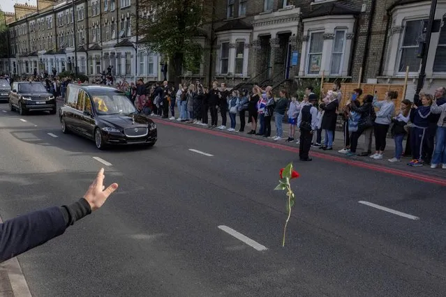 A person throws a flower towards Britain's Queen Elizabeth's coffin, as it is transported, on the day of her state funeral and burial, in London, Britain on September 19, 2022. (Photo by Carlos Barria/Reuters)