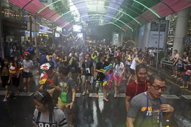 Revelers carry water guns as they participate in a water fight during Songkran Festival celebrations at Silom road in Bangkok April 12, 2015. (Photo by Athit Perawongmetha/Reuters)