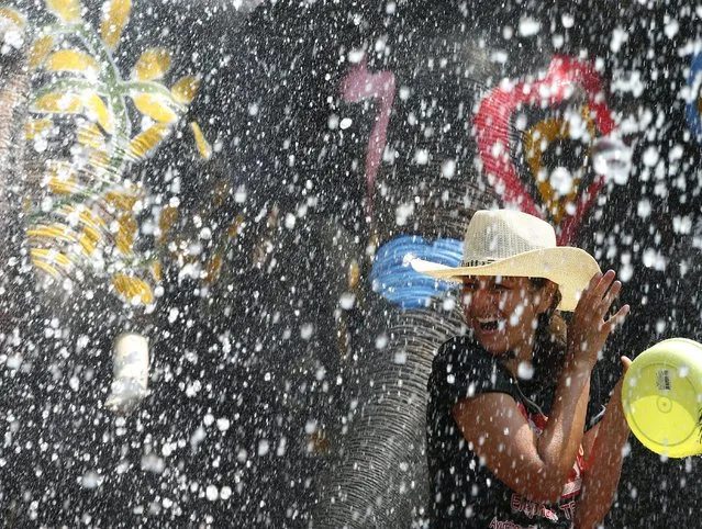 A foreigner reacts as she gets sprayed with water from elephants to preview the upcoming Songkran Festival celebration, the Thai traditional New Year, also known as the water festival at the ancient world heritage city of Ayutthaya, Thailand, 10 April 2015. (Photo by Narong Sangnak/EPA)