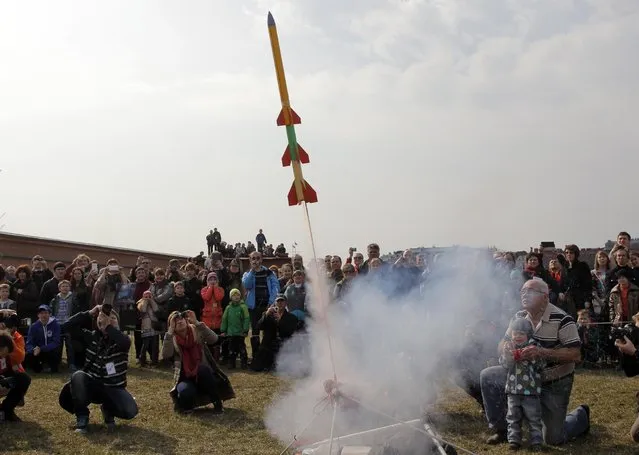 People watch the launch of a model rocket during a celebration of the 54th anniversary of Russia's Yuri Gagarin's first manned flight into space, in St. Petersburg, Russia, Sunday, April 12, 2015. (Photo by Dmitry Lovetsky/AP Photo)