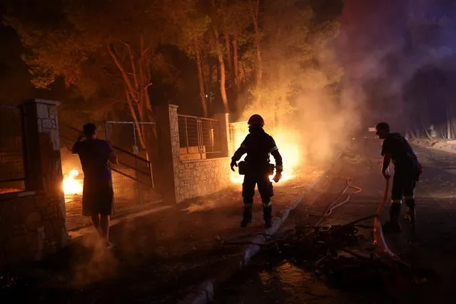 Firefighters try to tackle a wildfire burning in the suburb of Thrakomakedones, north of Athens, Greece, August 7, 2021. (Photo by Giorgos Moutafis/Reuters)