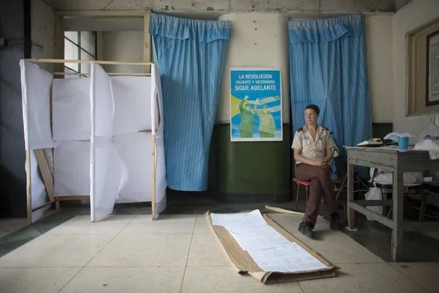 Caretaker Adriana Haedo, 40, sits beside a poster of former Cuban leader Fidel Castro (L) and his brother President Raul Castro at a polling station to be used for the municipal elections, in Havana April 18, 2015. (Photo by Alexandre Meneghini/Reuters)