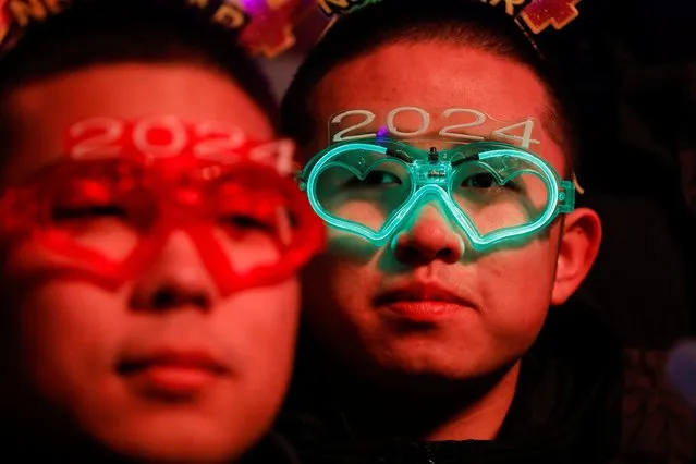 People wear party glasses during the New Year's countdown event at the Shougang Park in Beijing on December 31, 2023. (Photo by Tingshu Wang/Reuters)