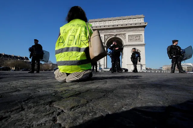 A protester wearing a yellow vest kneels on the Champs Elysees near the Arc de Triomphe during a demonstration by the “yellow vests” movement in Paris, France, February 23, 2019. Message reads, “Mr Macron, What is my Future”. (Photo by Philippe Wojazer/Reuters)