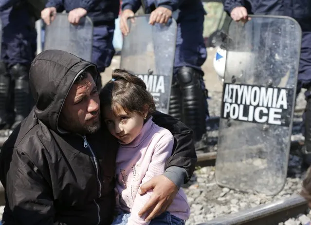 A migrant with a child sits in front of a line of Greek policemen on the railway tracks at the Greek-Macedonian border, near the village of Idomeni, Greece March 3, 2016. (Photo by Marko Djurica/Reuters)