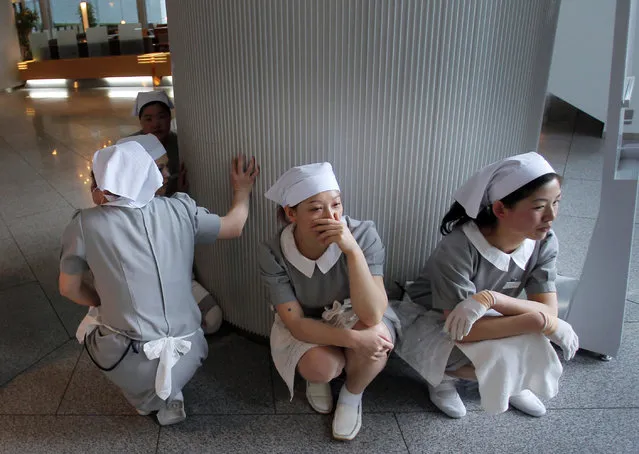 In this March 11, 2011 file photo, hotel employees squat down in horror at the hotel's entrance in Tokyo after a strong earthquake hit Japan. “I was at my desk watching the prime minister getting questioned in Parliament on TV when an ominous message from Japan's disaster early-warning system flashed on the screen: A major earthquake was about to strike. . (Photo by Itsuo Inouye/AP Photo)