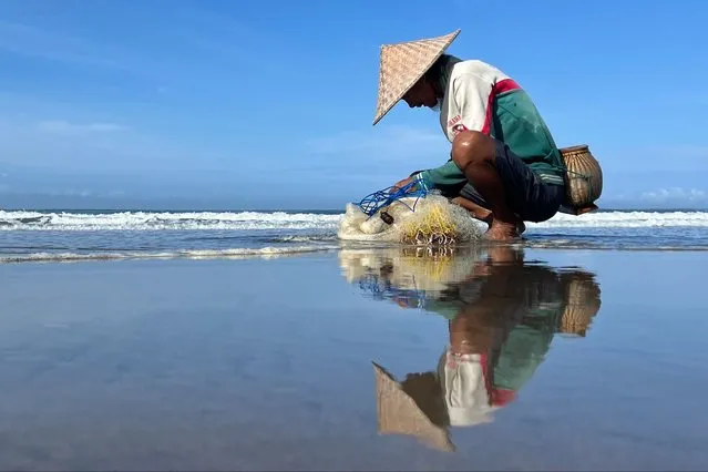 A fisherman checks the catch in his net at the beach in the Kerobokan district of Indonesia's resort island of Bali on January 17, 2023. (Photo by David Gannon/AFP Photo)