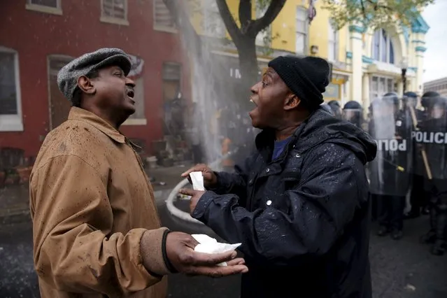 A Baltimore resident (R) trying to restore order in his neighborhood speaks to a protester during clashes in Baltimore, Maryland April 27, 2015. (Photo by Jim Bourg/Reuters)