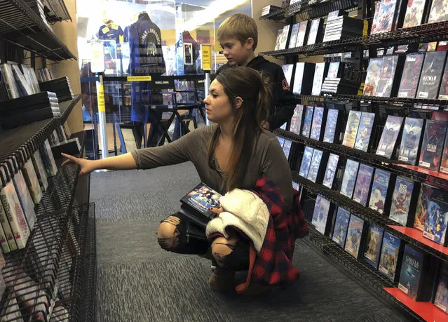 Tia Thiel and her son, Micah Knox, 7, browse a selection of movies at the last Blockbuster on the planet in Bend, Ore., on Monday, March 11, 2019. Thiel is a regular at the store and says she goes to the store for the older movies she can't find on streaming services like Netflix. When a Blockbuster in Perth, Australia, shuts its doors for the last time on March 31, the store in Bend, Ore., will be the only one left on Earth, and most likely in the universe. (Photo by Gillian Flaccus/AP Photo)