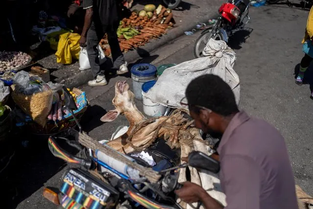 A man unties a goat from his motorcycle to take it for sale at a market in Port-au-Prince, Haiti on July 17, 2021. (Photo by Ricardo Arduengo/Reuters)