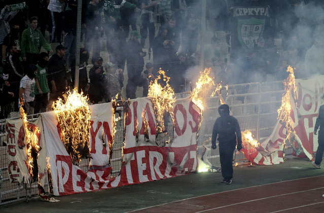 Fans burn a banner in front of stands during a Greek Super League soccer match inside the Athens' Olympic stadium, in Athens, Sunday, March 17, 2019. The derby between Greek league archrivals Panathinaikos and Olympiakos has been abandoned after a small number of Panathinaikos fans clashed with police outside Athens' Olympic stadium. (Photo by InTime Sports via AP Photo)