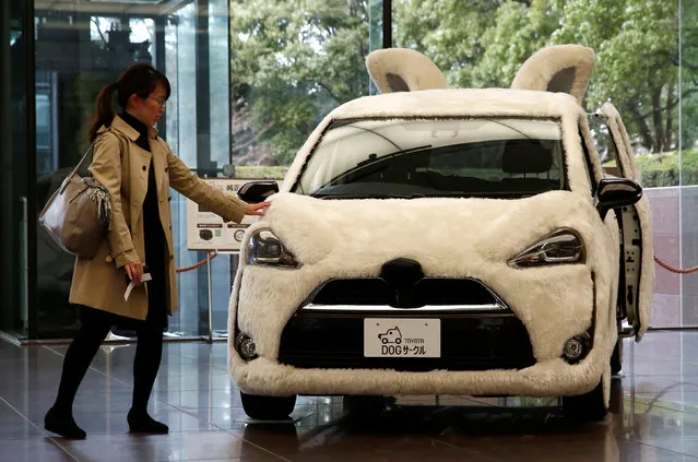 A woman touches Toyota's vehicle decorated as shape of dog at its headquarters in Tokyo, Japan, February 6, 2017. (Photo by Kim Kyung-Hoon/Reuters)