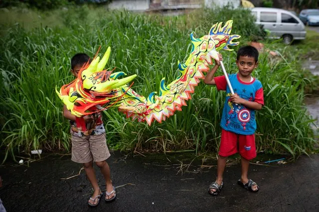 Boys hold a dragon toy as community members practise to perform a traditional lion dance ahead of the Chinese Lunar New Year of the Dragon at an abandoned factory in Bogor, West Java on February 6, 2024. (Photo by Aditya Aji/AFP Photo)