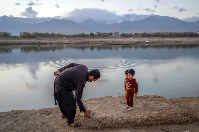 A man plays with his children next to Qargha Reservoir on the outskirts of Kabul on October 26, 2021. (Photo by Bulent Kilic/AFP Photo)