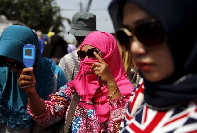 An Indonesian woman holds a mirror as she tries on new sunglasses at a stall at Tanah Abang weekly market in Jakarta, May 7, 2015. (Photo by Reuters/Beawiharta)