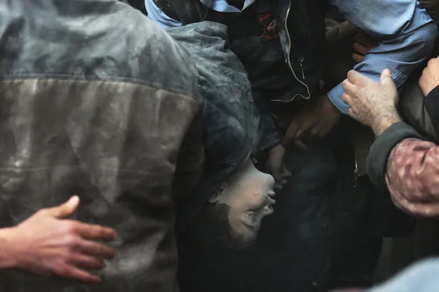 Men carry a body of a boy, removed from under rubble, at a site hit by what activists said was an airstrike by forces loyal to Syrian President Bashar al-Assad in the Duma neighbourhood of Damascus January 7, 2014. (Photo by Bassam Khabieh/Reuters)