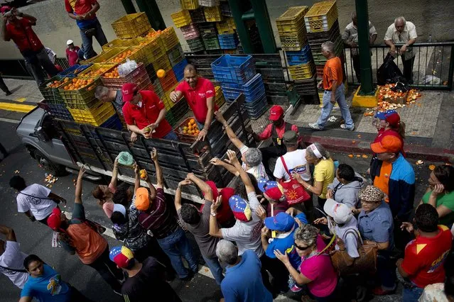 Government workers give oranges to elderly people attending a pro-government march in Caracas, on February 23, 2014. (Photo by Rodrigo Abd/Associated Press)
