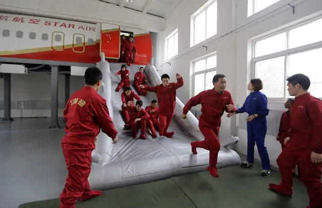 Trainees of the Tianjiao Special Guard/Security Consultant bodyguard training camp practice emergency evacuation from a scale model of a passenger jet 
during a special course on flight safety at a flight attendant training centre on the outskirts of Beijing, March 18, 2014. (Photo by Jason Lee/Reuters)