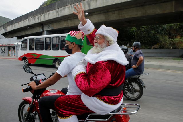 A man dressed as Santa Claus rides on a motorcycle during a Christmas toy distribution organized by a Venezuelan journalists group, in Caracas, Venezuela on December 17, 2021. (Photo by Leonardo Fernandez Viloria/Reuters)