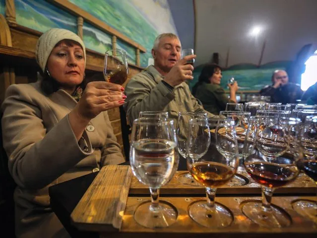 Visitors participate in a wine tasting as part of a guided tour to the wine cellars and museum galleries of the Massandra winery in Massandra village near Yalta. (Photo by Sergei Ilnitsky/EPA)