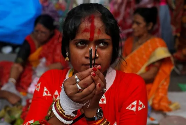 A woman worships Hindu goddess Bipadnashini during a religious ceremony, in which married women fast for whole day for the betterment of their family, in a temple premises in Kolkata, India, July 9, 2019. (Photo by Rupak De Chowdhuri/Reuters)