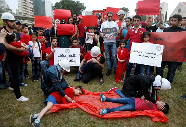 Syrian protesters wear civil defence helmets during a re-enactment of the deaths of Aleppo's children in the Syrian civil war as they take part in a sit-in in solidarity with the people of Aleppo, in front of the offices of the U.N. headquarters in Beirut, Lebanon May 1, 2016. (Photo by Mohamed Azakir/Reuters)