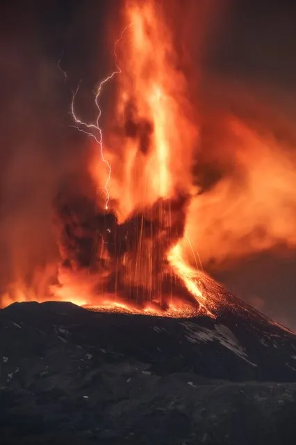 A volcanic thunderstorm over Mt. Etna, Sicily, Italy, generates volcanic lightning during an eruption, early Friday, February 11, 2022. Colliding particles of volcanic ash generate static electricity that discharges within the volcanic plume. (Photo by Emilio Messina/AP Photo)