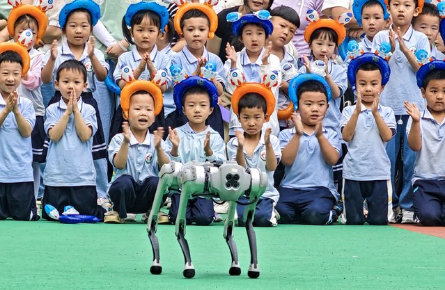Children watch a robotic dog performing at a kindergarten before the International Children's Day on May 28, 2024 in Hanzhong, Shaanxi Province of China. (Photo by Liu Xiaodong/VCG via Getty Images)