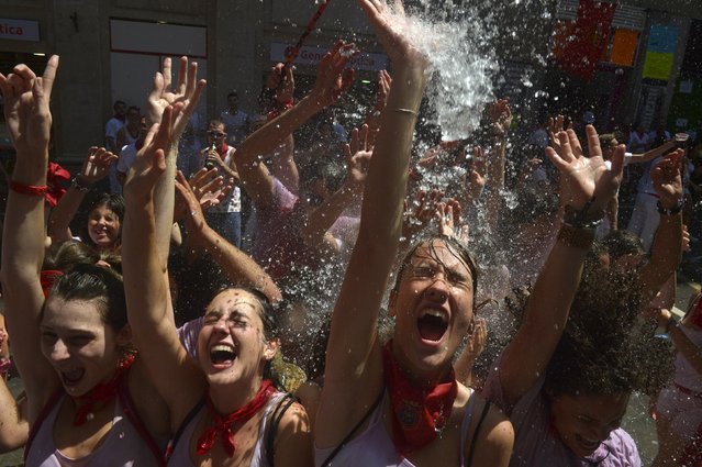 Revellers cool off with water thrown from a balcony at the start of the San Fermin festival in Pamplona, Spain July 6, 2015. (Photo by Vincent West/Reuters)