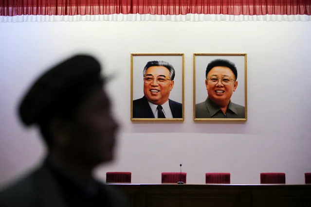 The manager of the Jangchon Vegetable Co-op farm is silhouetted in front of pictures of former North Korean leaders Kim Il Sung and Kim Jong Il as he speaks to foreign reporters visiting just outside Pyongyang, North Korea May 4, 2016. (Photo by Damir Sagolj/Reuters)