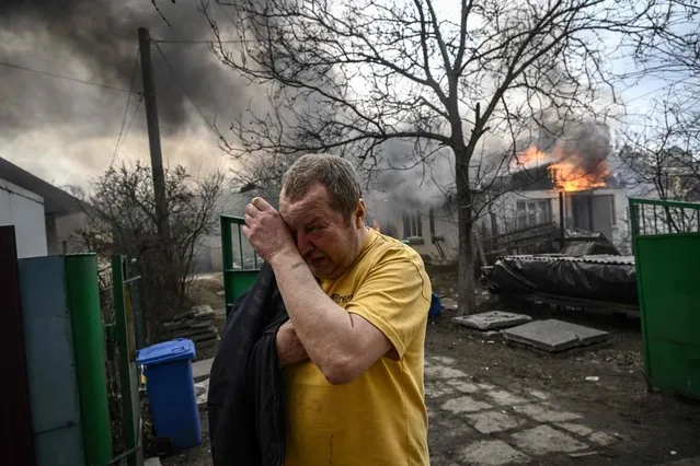 Yevghen Zbormyrsky, 49, reacts in front of his burning home after it was hit by a shelled in the city of Irpin, outside Kyiv, on March 4, 2022. The UN Human Rights Council on March 4, 2022, overwhelmingly voted to create a top-level investigation into violations committed following Russia's invasion of Ukraine. (Photo by Aris Messinis/AFP Photo)