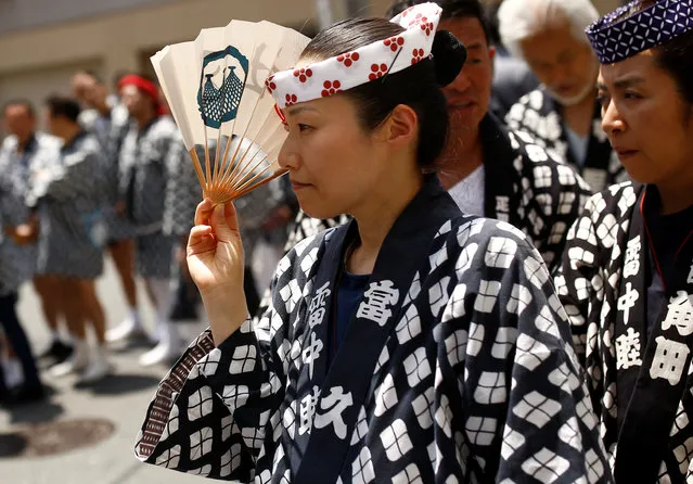 A woman dressed in traditional local clothes holds a fan during the Sanja festival in Tokyo's Asakusa district, Japan, May 15, 2016. (Photo by Thomas Peter/Reuters)