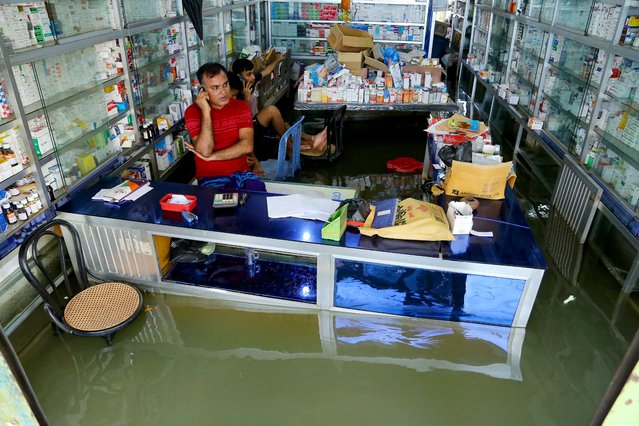 Shopkeepers attend a phone call as they wait for customers at a medical store in Fenchuganj, in Sylhet on July 3, 2024. Six people have been killed in floods precipitated by torrential rains across northeast India and neighbouring Bangladesh that inundated the homes of more than a million others, officials said on July 3. (Photo by Mamun Hossain/AFP Photo)