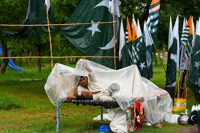 A vendor looks on as he sells Pakistan’s national flags along a street, amid rainfall in Islamabad on August 7, 2024, ahead of the country's independence day. (Photo by Aamir Qureshi/AFP Photo)