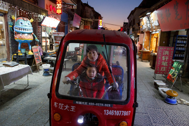 A woman and a child ride an electric tricycle in the old town of Luoyang, Henan province, China on January 21, 2019. (Photo by Thomas Peter/Reuters)