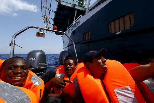 Migrants sit in a Migrant Offshore Aid Station (MOAS) RHIB (Rigid-hulled inflatable boat) as they arrive alongside the MOAS ship MV Phoenix, some 20 miles (32 kilometres) off the coast of Libya, August 3, 2015. Some 118 migrants were rescued from a rubber dinghy off Libya on Monday morning. (Photo by Darrin Zammit Lupi/Reuters)