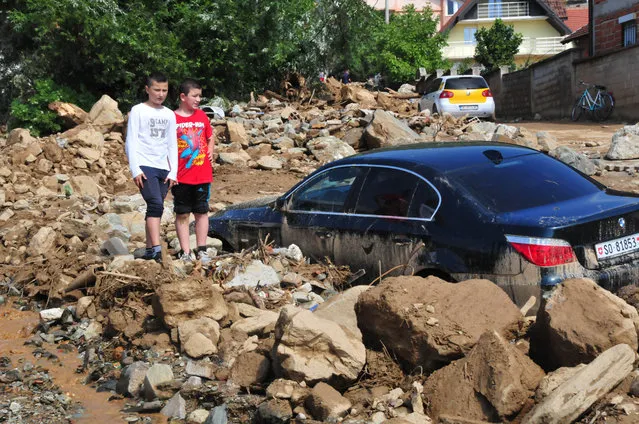 Children look at a destroyed car in a pile of mud, stones and debris after a flood in the village of Golema Recica, just near the town of Tetovo, in northwestern Macedonia, on Tuesday, August 4, 2015. (Photo by Zoran Andonov/AP Photo)