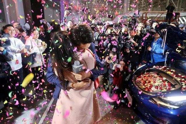 A Tesla employee proposes to his girlfriend with a China-made Tesla Model 3 vehicle filled with flowers at a delivery ceremony in the Shanghai Gigafactory of the U.S. electric car maker in Shanghai, China on December 30, 2019. (Photo by Yilei Sun/Reuters)